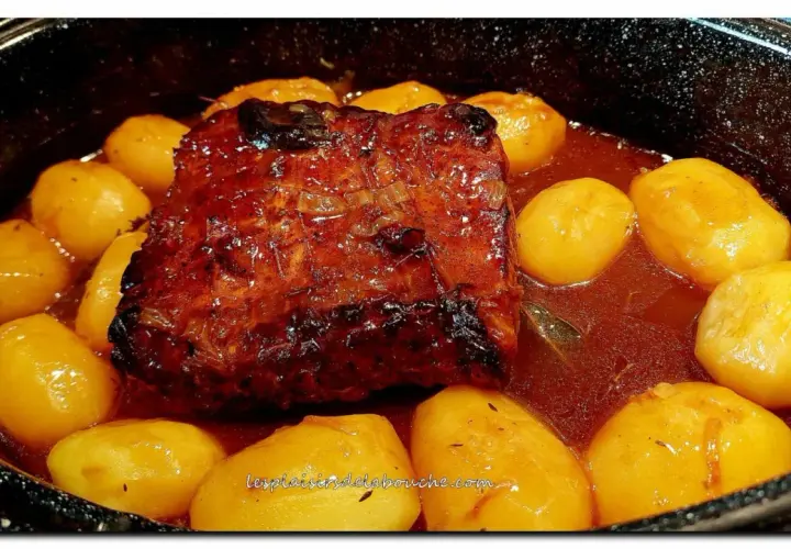 Un rôti de porc à la cocotte en sauce, doré et savoureux, mijote avec des pommes de terre fondantes. Un plat réconfortant prêt à être dégusté.