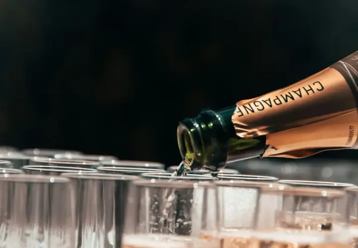 Une bouteille de champagne verse dans des flûtes alignées. Le choix idéal pour quel champagne choisir pour l'apéritif.