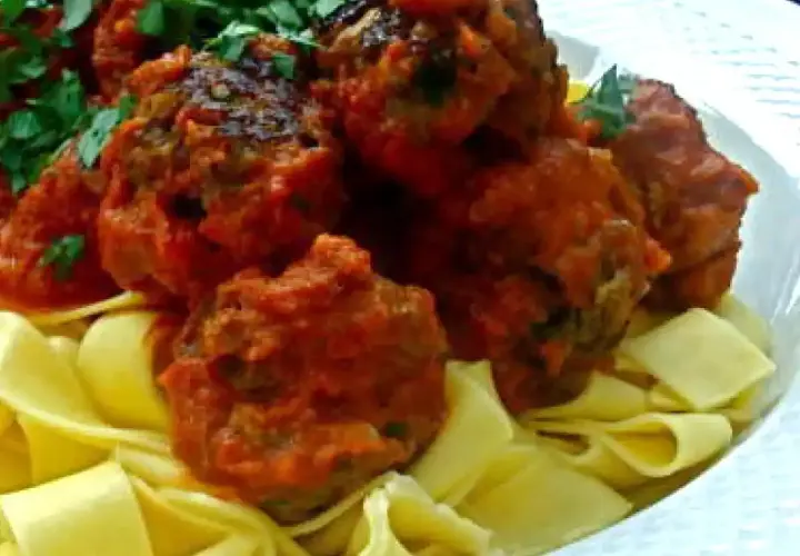 Boulettes de viande italienne savoureuses en sauce tomate, servies sur des pâtes fraîches. Une recette parfaite pour un repas réconfortant.
