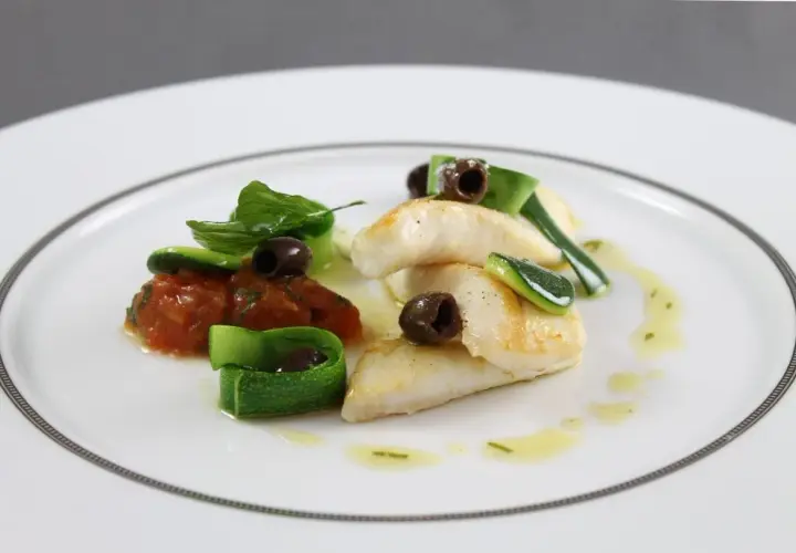 Délicieux filet de saint pierre poêlé, servi avec une concassée de tomates, des rubans de courgette et des olives noires.