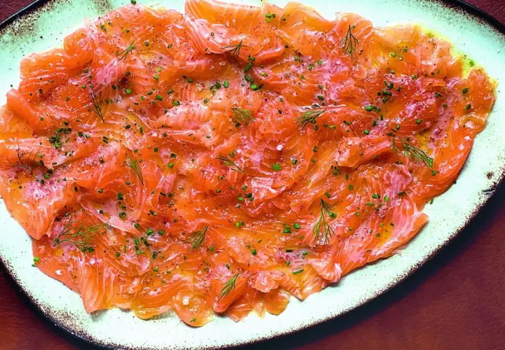 Délicieux carpaccio de saumon finement tranché, parsemé d'aneth frais et de ciboulette ciselée. Un plat léger et savoureux.
