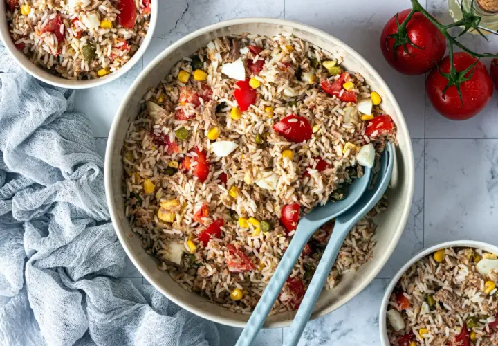 Un grand bol de salade de riz thon, garnie de tomates, maïs et œufs durs. Parfait pour un repas léger et savoureux.