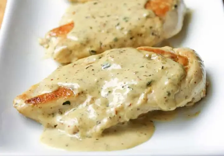 Deux tendres poitrines de poulet à la crème, nappées d'une sauce onctueuse aux herbes, prêtes à être dégustées.
