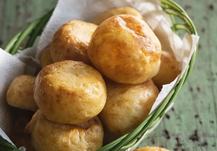 Petits pains dorés, une délicieuse recette de manioc, servis dans un panier en osier garni de papier blanc.