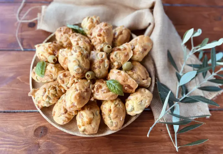 Plate of savory madeleines with olives and basil, perfect for an aperitif.