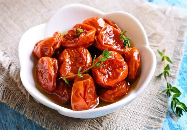Tomates séchées confites dans de l'huile d'olive, garnies de thym frais. Une recette rapide pour un goût intense.