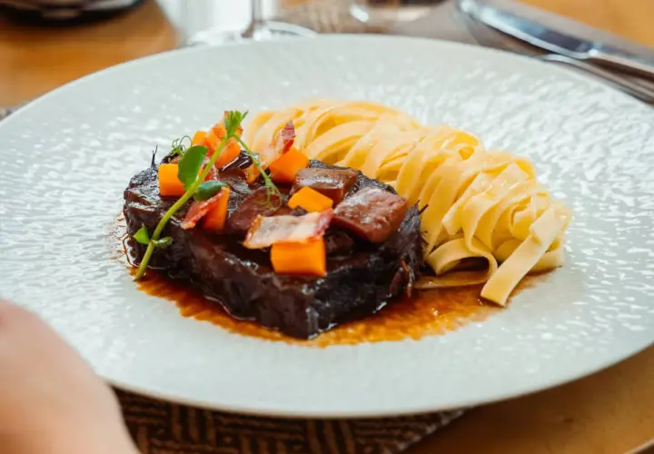 Un paleron de bœuf braisé, garni de dés de carottes et de lardons, servi avec des tagliatelles fraîches. Une recette savoureuse à découvrir.