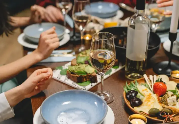 Un verre de Gewurztraminer accompagne un plateau de fromages, olives et fruits, ainsi que des toasts à l'avocat. Un repas convivial.