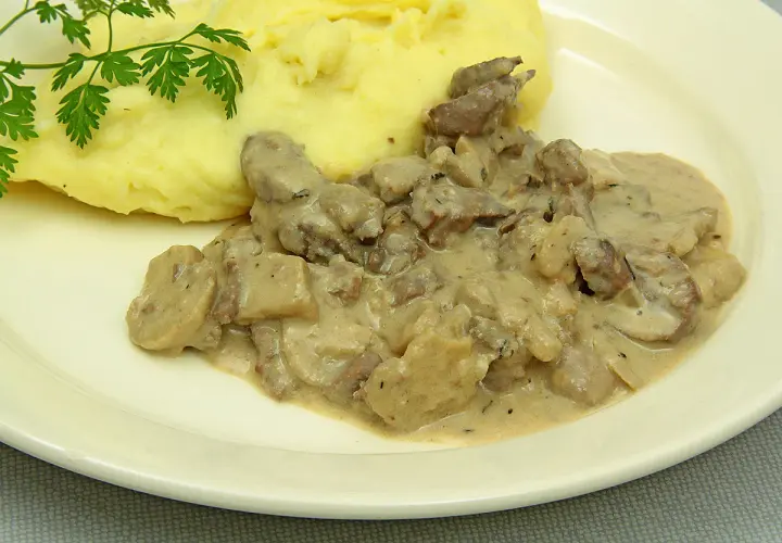 Rognons de porc en sauce crémeuse avec des champignons, servis avec une purée de pommes de terre onctueuse. Parfait pour savoir avec quoi accompagner des rognons de porc.