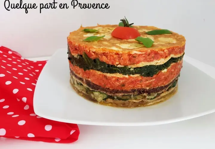 Un délicieux gâteau d'omelette provençale, aux couches colorées de légumes et de sauce tomate, garni d'une tomate cerise.