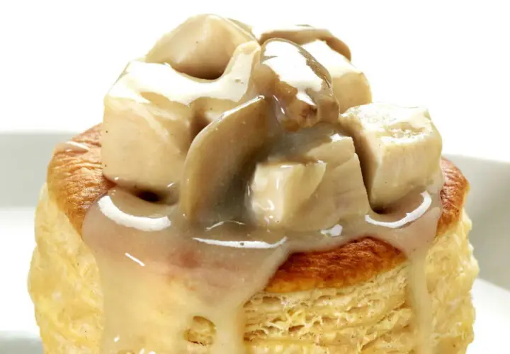 Une bouchée à la reine poulet, garnie de morceaux de volaille et d'une sauce crémeuse aux champignons, sur une pâte feuilletée dorée.