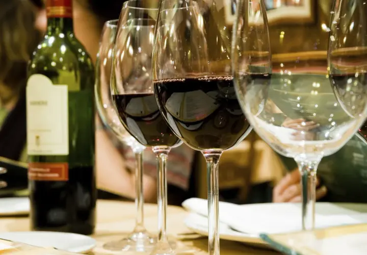 Bouteille de vin vert et verres remplis, révélant la belle couleur du vin rouge profond.