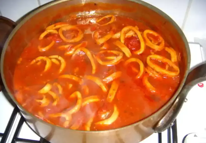 Calamars à l'armoricaine mijotant dans une sauce tomate savoureuse. Un plat réconfortant prêt à être dégusté.