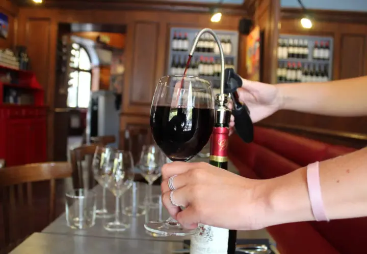 Service d'un vin rouge ouvert avec un tire-bouchon à pompe. La conservation du vin est assurée.