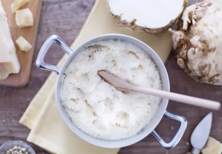 Un crémeux **purée de céleri** dans une casserole, avec du céleri-rave, du parmesan et du poivre.