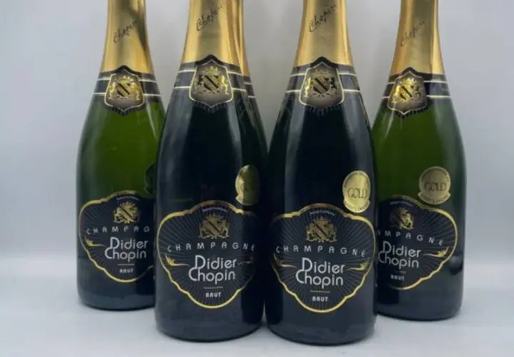 Quatre bouteilles de champagne Didier Chopin Brut, deux en verre sombre et deux en verre vert, avec leurs étiquettes noires et dorées. Un avis sur champagne Didier Chopin.