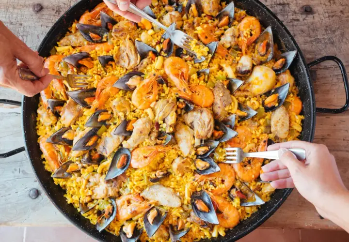 Un plat généreux de riz façon paella, garni de crevettes, moules et morceaux de poulet, prêt à être dégusté.