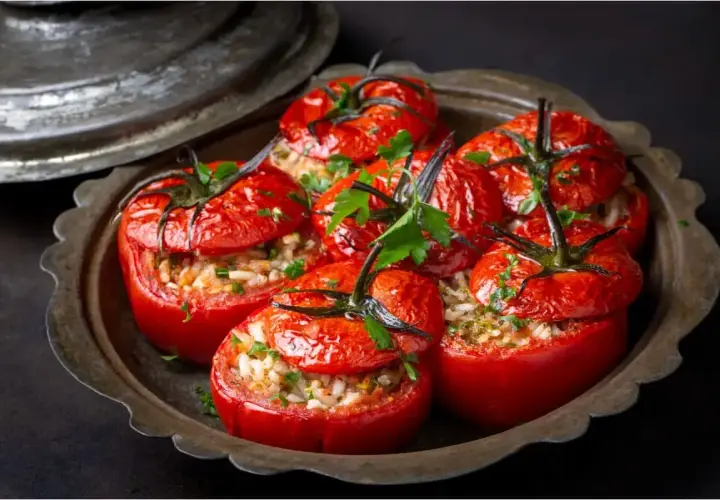 Tomates farcies au riz, garnies de persil frais, servies dans un plat en métal vieilli. Un délice simple et savoureux.