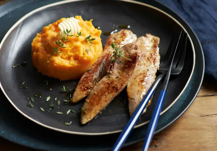 Trois aiguillettes de canard poêlées, servies avec une purée de patate douce onctueuse, garnie de thym frais et d'une noix de beurre.