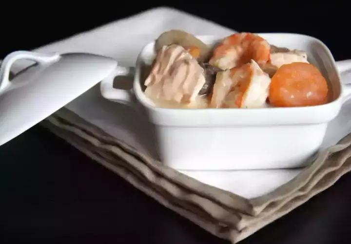 Blanquette de saumon et crevettes, nappée d'une sauce onctueuse au vin blanc, servie dans un ramequin blanc.