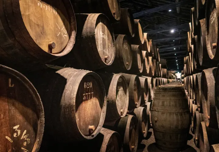 Cave à vin sombre remplie de nombreux fûts en bois empilés.