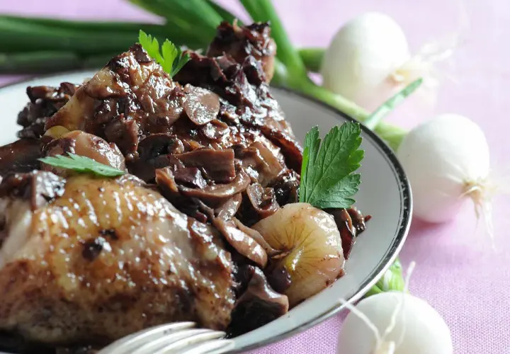 Coq au vin savoureux, garni de champignons et d'oignons. Parfait pour savoir que boire avec un coq au vin.