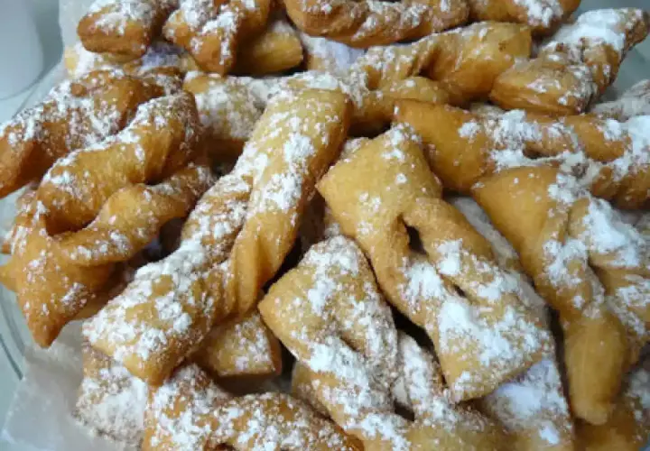 Une assiette généreuse de bugnes lyonnaises dorées, saupoudrées de sucre glace. La meilleure recette de bugnes lyonnaises pour un goûter gourmand.