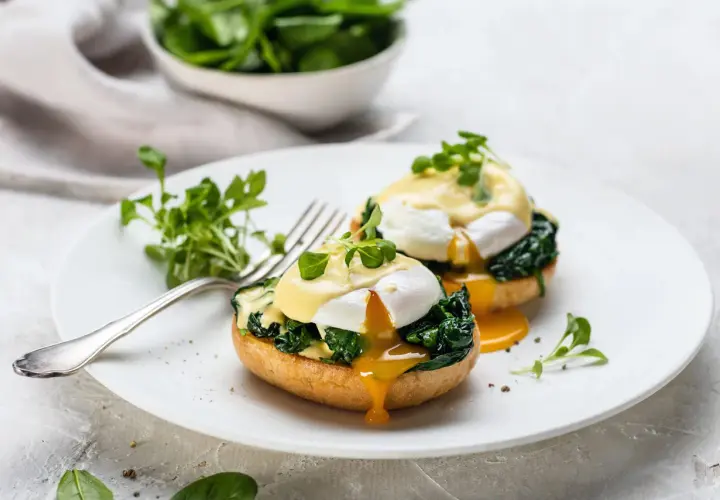 Deux œufs pochés sur des muffins anglais, recouverts de sauce hollandaise et d'épinards. Un déliceux œuf florentin prêt à être dégusté.