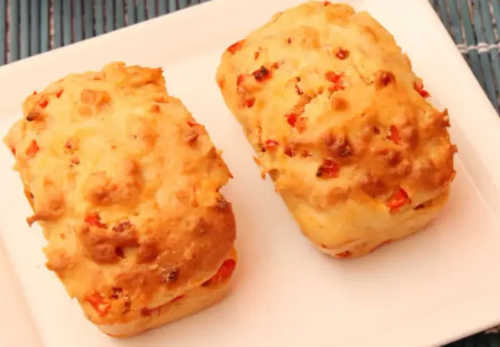 Deux petits pains dorés, un délicieux cake aux légumes, sont servis sur une assiette blanche.