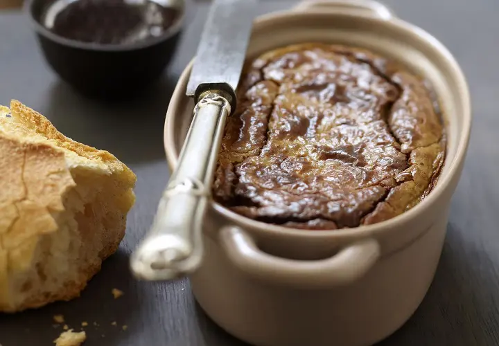 Un délicieux gâteau de foie de volaille à l'ancienne, servi avec du pain croustillant et une petite coupelle de confiture.