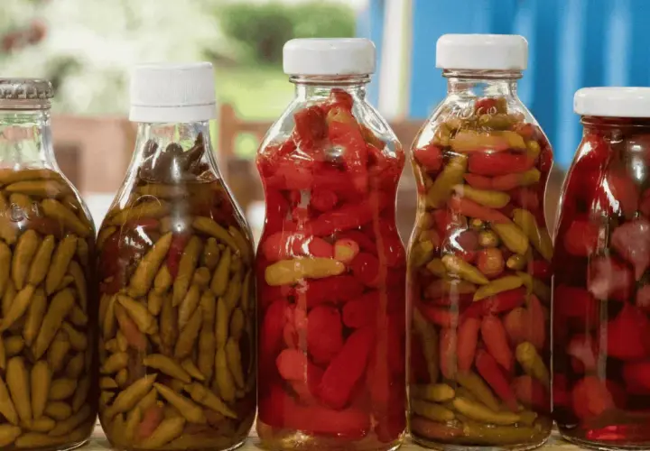 Bouteilles de piments verts et rouges marinés, prêts pour une recette de pickles maison.