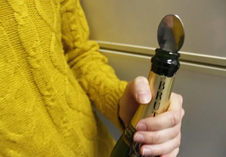 Une cuillère est insérée dans le goulot d'une bouteille de champagne pour montrer comment refermer une bouteille de champagne.