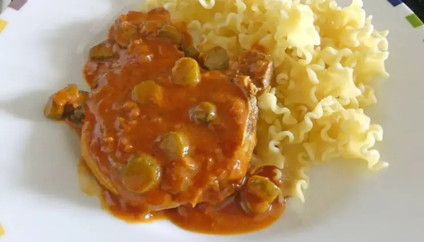Côtes de porc sauce charcutière, un plat savoureux avec des pâtes frisées.