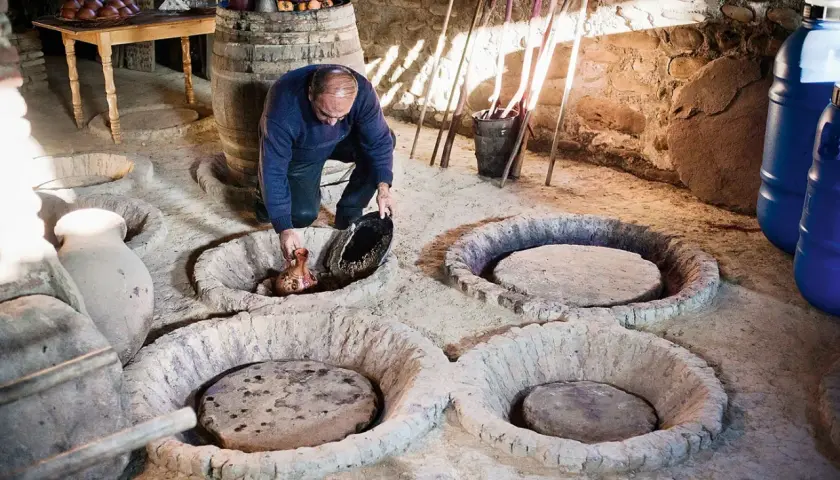Un homme verse du jus de raisin dans une cuve en terre, peut-être pour recréer la méthode ancestrale qui a inventé le vin.