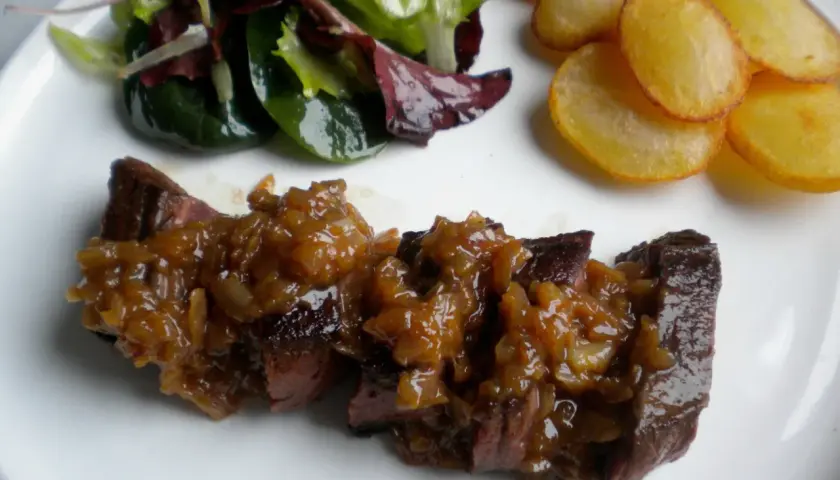 Un onglet à l'échalote, servi avec une salade verte et des pommes de terre sautées. Un plat savoureux et coloré.