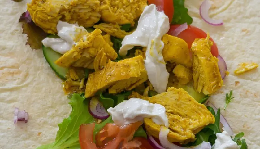 Un délicieux chawarma poulet garni de légumes frais et de sauce blanche crémeuse, prêt à être dégusté.