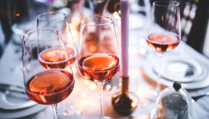 Verres remplis de bon vin rose, prêts pour une célébration festive avec des bougies et des lumières douces.