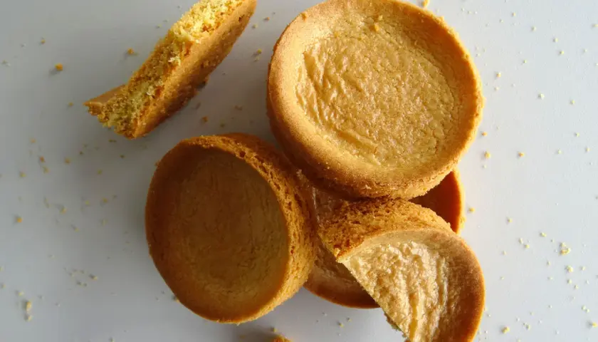 Des biscuits sablés bretons éparpillés, certains entiers, d'autres brisés, sur un fond clair.