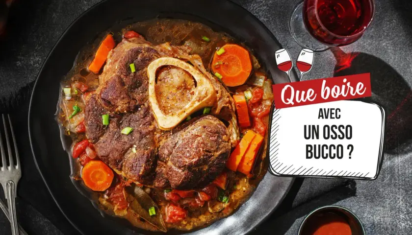Un plat d'osso bucco savoureux, avec carottes et tomates, servi dans une assiette noire. La question "Que boire avec un osso bucco ?" est affichée à côté d'un verre de vin rouge.