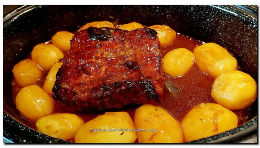 Un rôti de porc à la cocotte en sauce, doré et savoureux, mijote avec des pommes de terre fondantes. Un plat réconfortant prêt à être dégusté.