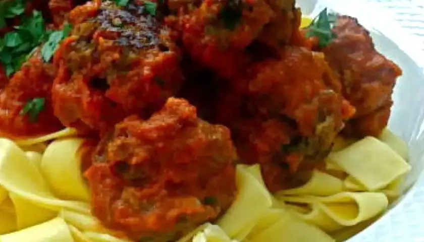 Boulettes de viande italienne savoureuses en sauce tomate, servies sur des pâtes fraîches. Une recette parfaite pour un repas réconfortant.