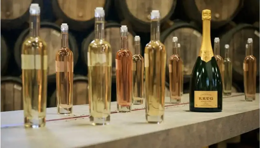 Bouteilles de champagne alignées, prêtes pour la production de champagne en France. Au fond, des tonneaux de vieillissement.