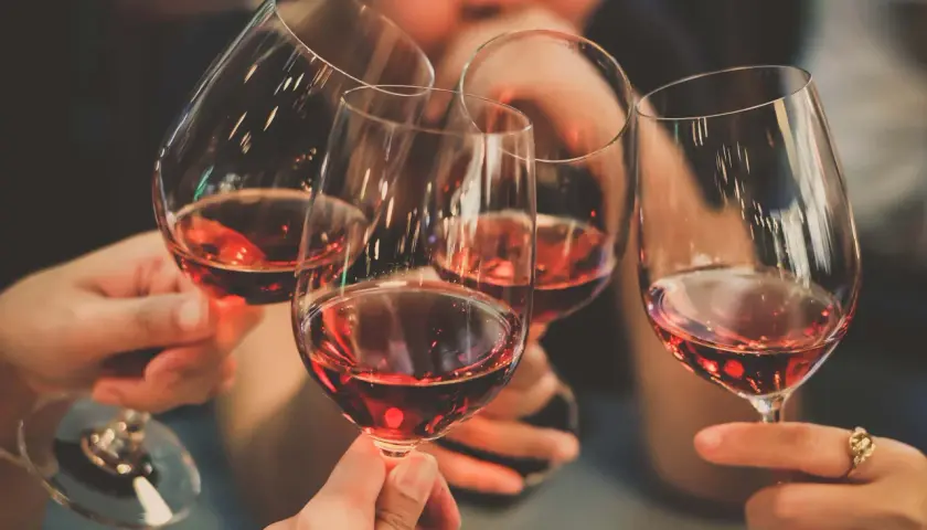 Des mains portent des verres de vin rouge, évoquant la convivialité et les riches régions viticoles de France.