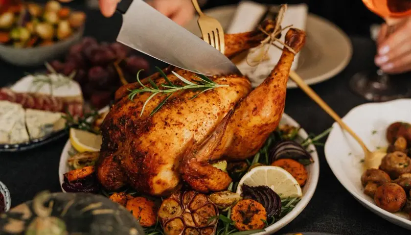 Une dinde rôtie, garnie de légumes et d'herbes, est découpée. Parfait pour savoir que boire avec une dinde farcie.