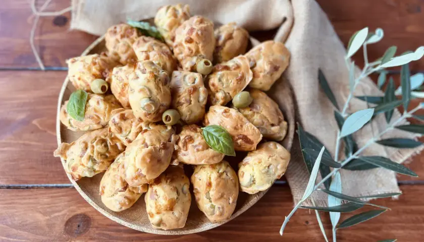 Plate of savory madeleines with olives and basil, perfect for an aperitif.