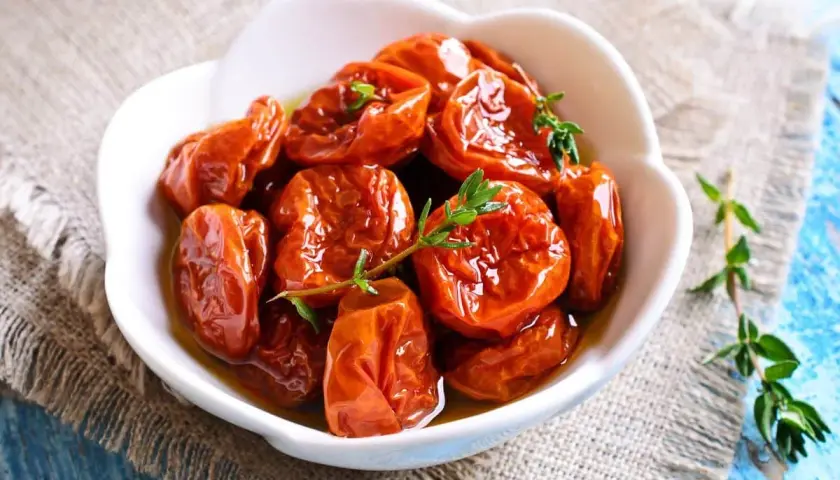 Tomates séchées confites dans de l'huile d'olive, garnies de thym frais. Une recette rapide pour un goût intense.