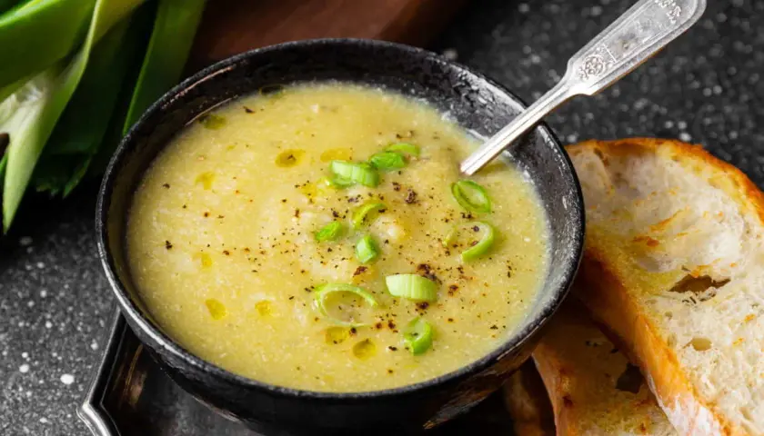Un réconfortant velouté de poireaux pommes de terre, garni de ciboule et servi avec du pain grillé.