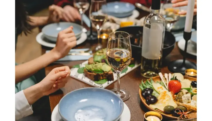 Un verre de Gewurztraminer accompagne un plateau de fromages, olives et fruits, ainsi que des toasts à l'avocat. Un repas convivial.