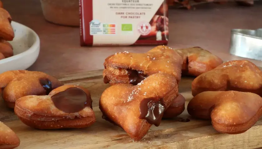Des cœurs gourmands de beignet au chocolat, certains saupoudrés de sucre, d'autres généreusement garnis de chocolat fondant.