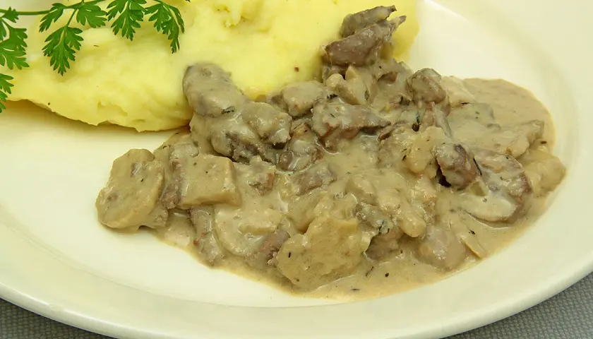 Rognons de porc en sauce crémeuse avec des champignons, servis avec une purée de pommes de terre onctueuse. Parfait pour savoir avec quoi accompagner des rognons de porc.
